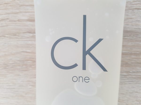 A bottle of ck one on a wooden table.
