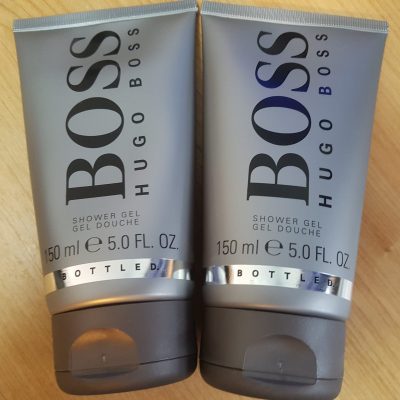 Two tubes of hugo boss shower gel on a wooden table.