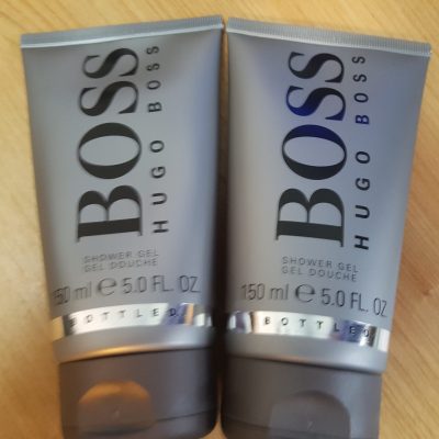 Two tubes of hugo boss shower gel sitting on a wooden table.