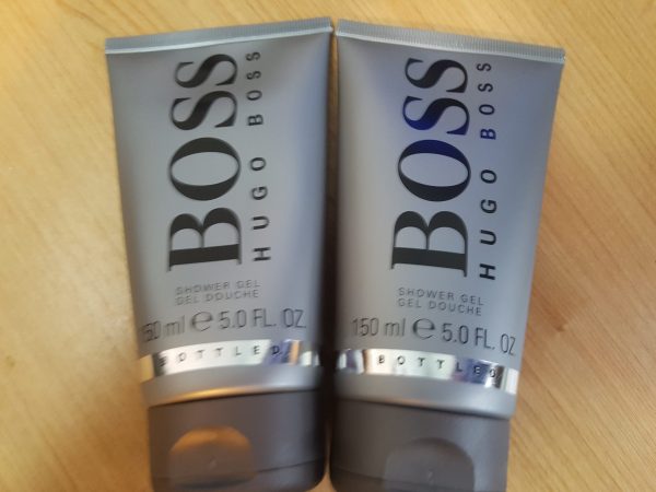 Two tubes of hugo boss shower gel sitting on a wooden table.
