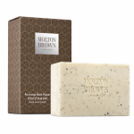 Molton Brown Black Pepper Bodyscrub Soap Bar, 250g, featuring a speckled texture, is displayed in front of its brown patterned packaging labeled "Re-charge Black Pepper.