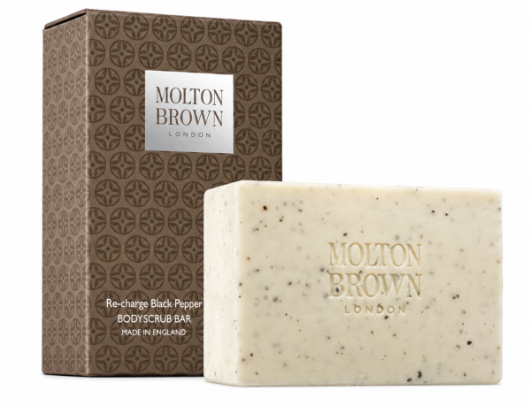 A rectangular Molton Brown Black Pepper Bodyscrub Soap Bar, 250g, sits in front of its brown, patterned box labeled “Re-charge Black Pepper.”.