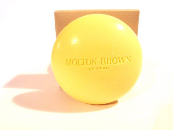 A yellow ball with the word Molton Brown Orange & Bergamot Perfumed Bar of Soap, 150g on it.