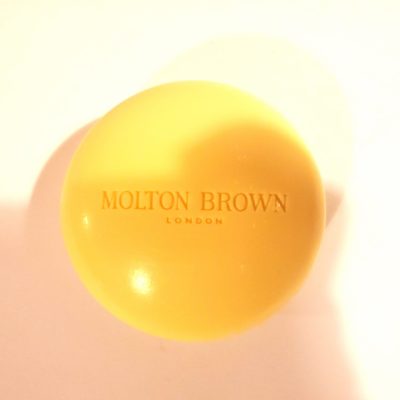 A yellow ball with the Molton Brown Orange & Bergamot Perfumed Bar of Soap, 150g on it.