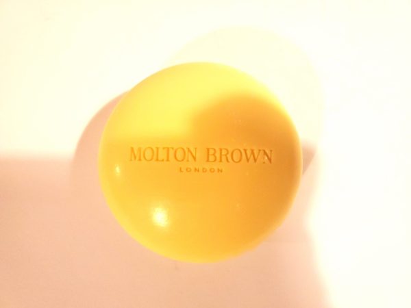 A yellow ball with the Molton Brown Orange & Bergamot Perfumed Bar of Soap, 150g on it.