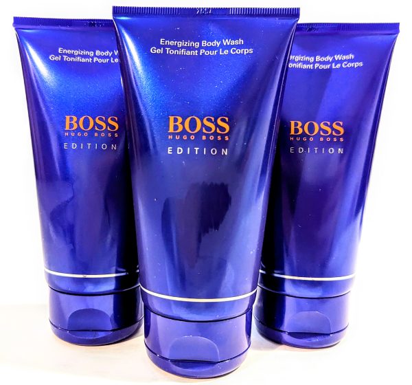 Three bottles of Hugo Boss energizing body wash on a reflective surface. Buy online.