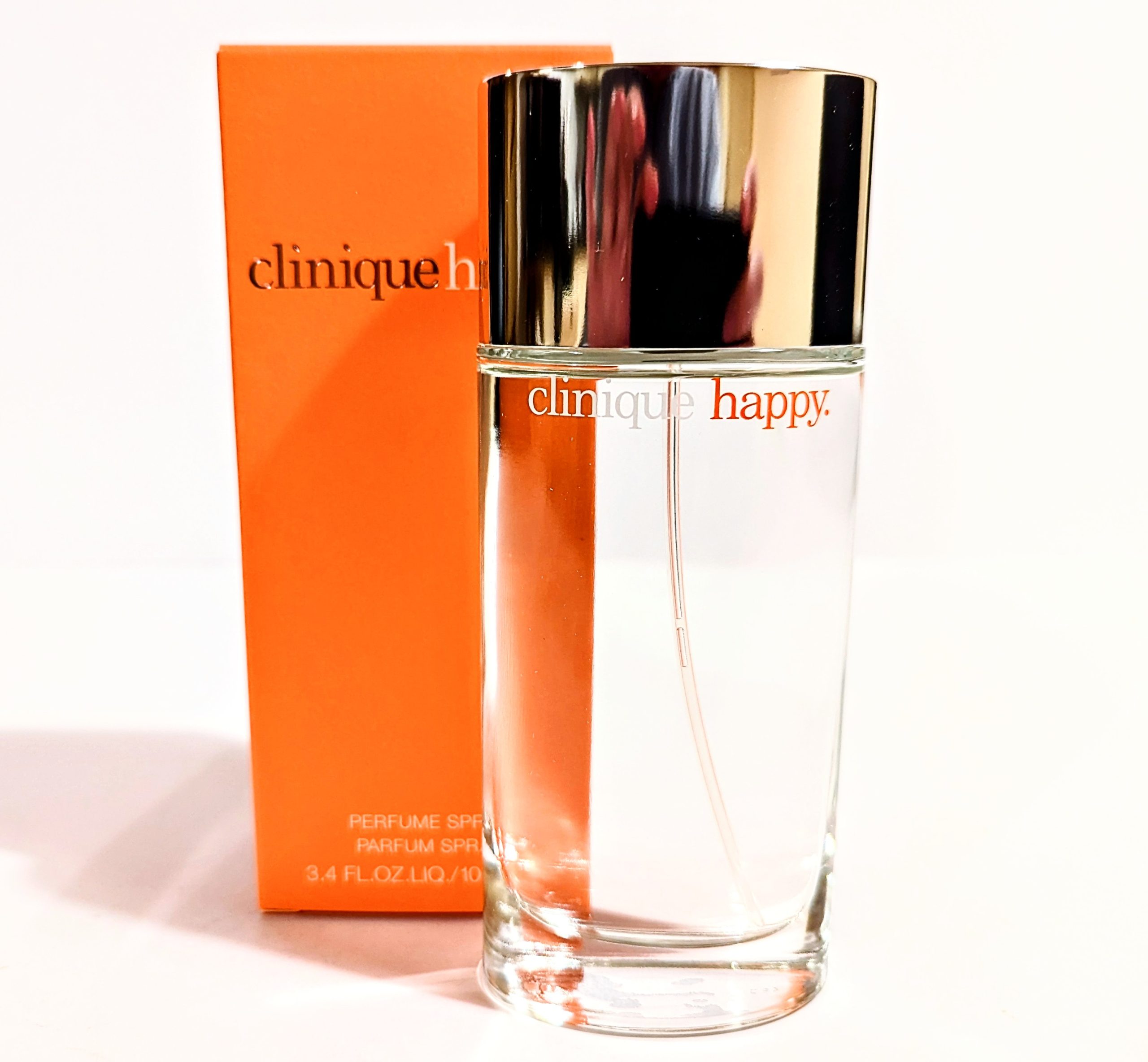 A bottle of Clinique Happy edp in front of a box.