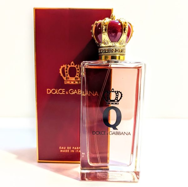 A bottle of dolce & gabbana "the one" perfume with a decorative crown cap beside its box.