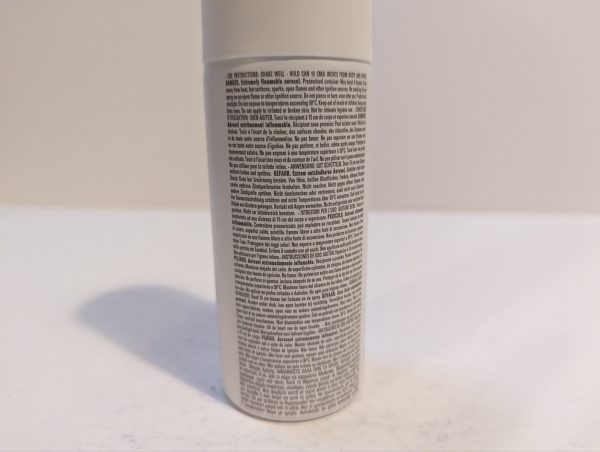 A bottle of hair spray sitting on a white surface.