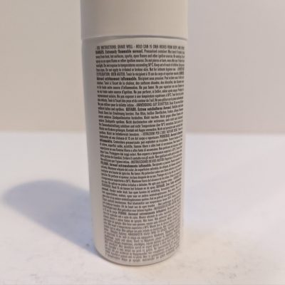 A bottle of hair spray sitting on a white surface.