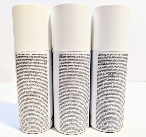 Three white spray cans on a white surface.