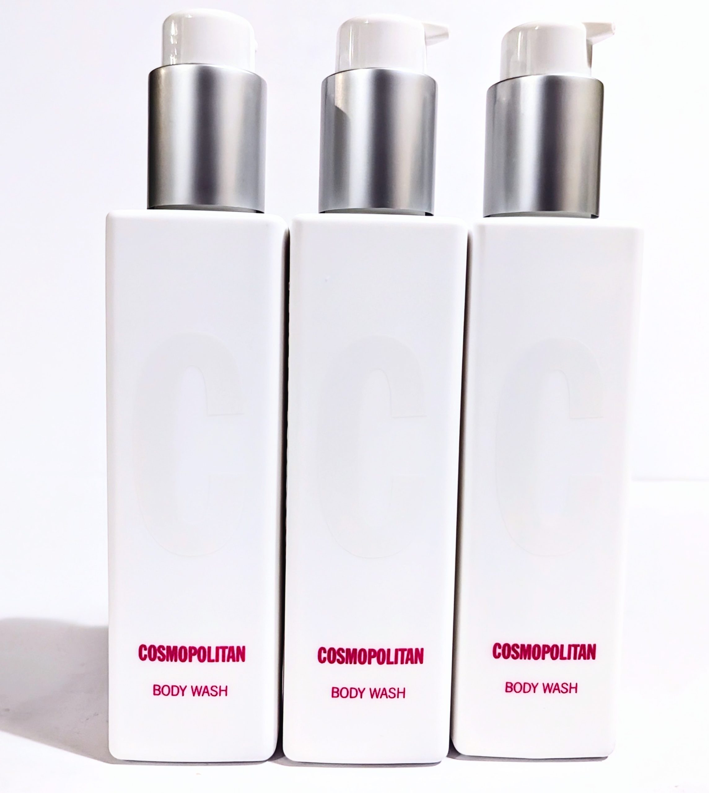 Three white bottles of Cosmopolitan Body Wash with pump dispensers, arranged side by side against a white background.