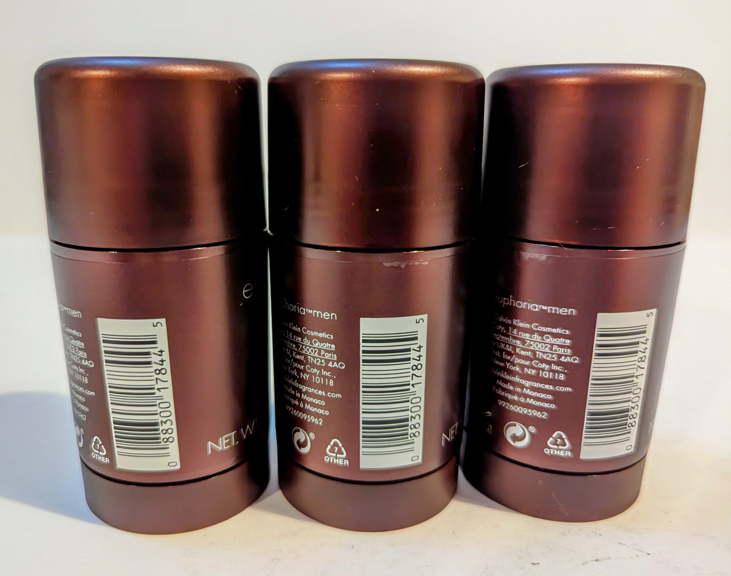 Three brown cylindrical deodorant sticks are placed side by side with their backs facing the camera, displaying the product labels and barcodes.