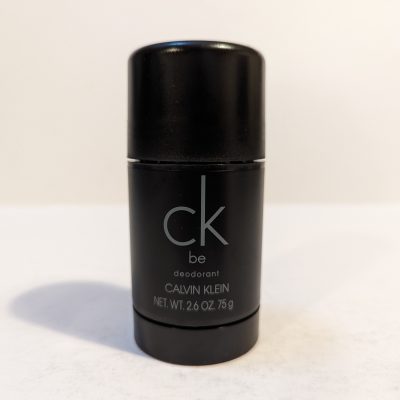 A black, cylindrical deodorant stick with "ck be" written on it in light gray text. The label indicates it is a Calvin Klein product with a net weight of 2.6 ounces (75 grams).