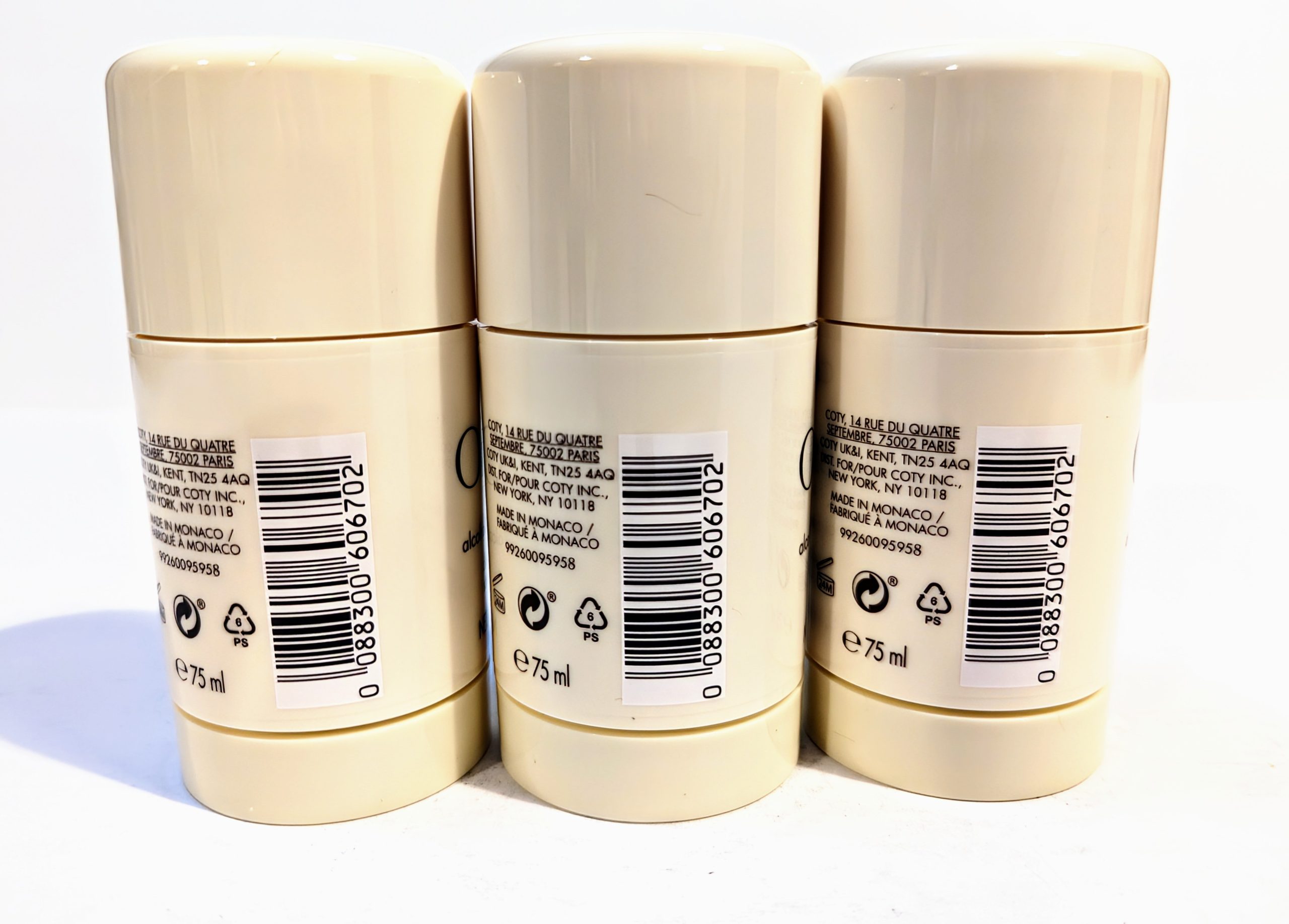 Three cream-colored cylindrical deodorant bottles with barcode labels and recycling symbols, standing upright in a row against a white background.