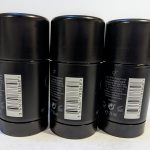 Three black deodorant sticks are arranged in a row, with barcodes and product information visible on the back labels.