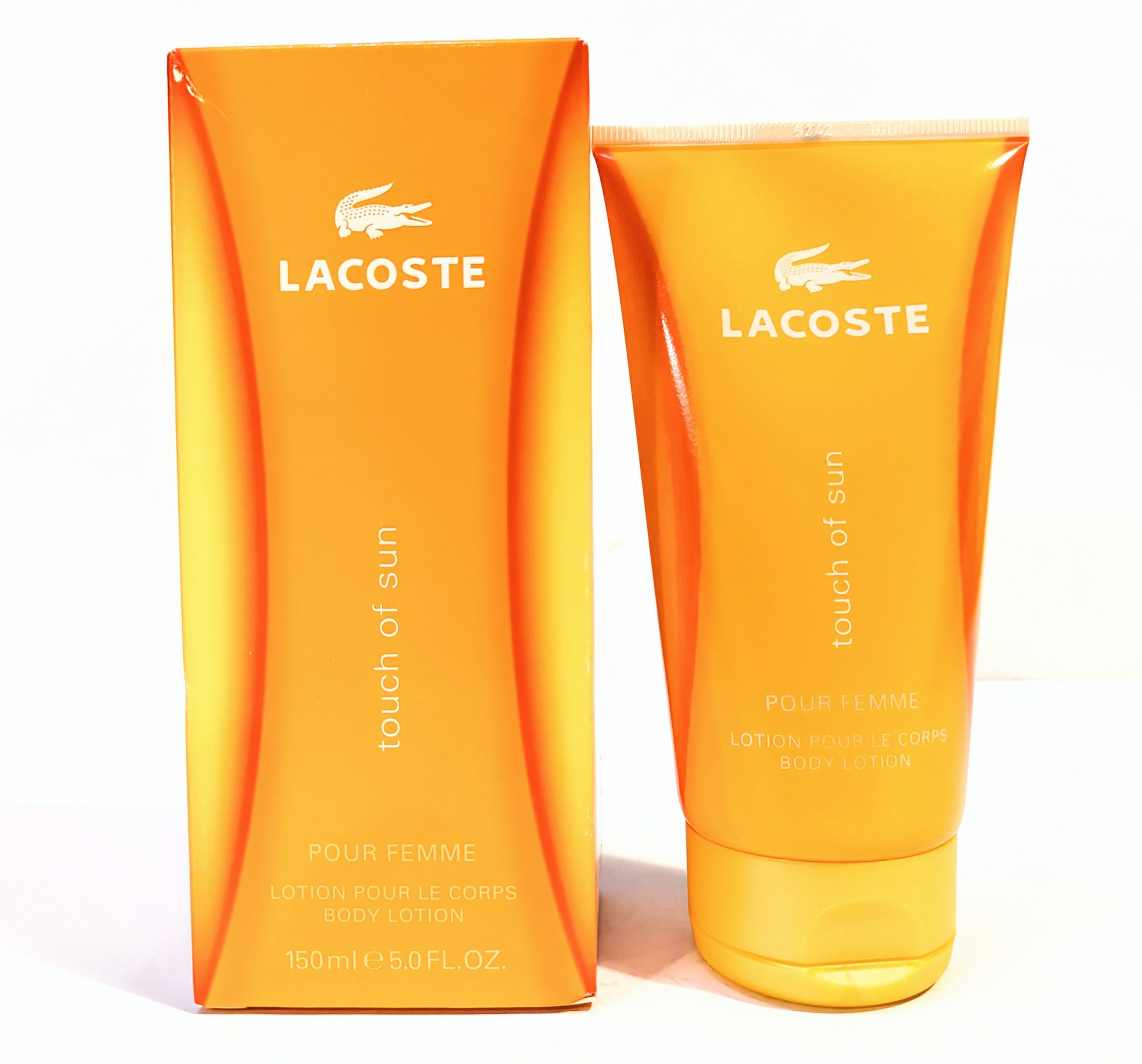 Lacoste “Touch of Sun” body lotion in a 150 ml orange tube, displayed with its matching orange box featuring the Lacoste logo and product name.