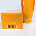 Close-up of an orange box and tube of a product labeled "touch of sun." The box features a barcode and symbols for recycling, while the tube is partially visible in the background.