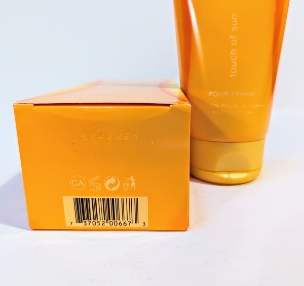 Close-up of an orange box and tube of a product labeled "touch of sun." The box features a barcode and symbols for recycling, while the tube is partially visible in the background.