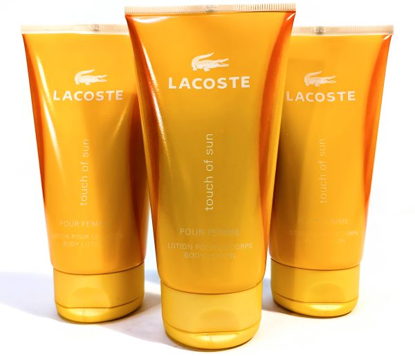 Three orange tubes of Lacoste "touch of sun" body lotion are displayed vertically, with the Lacoste logo and product name visible on each tube.