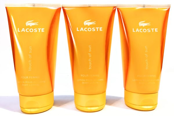 Three orange tubes of Lacoste Touch of Sun Pour Femme body lotion, each with a white Lacoste logo and text.