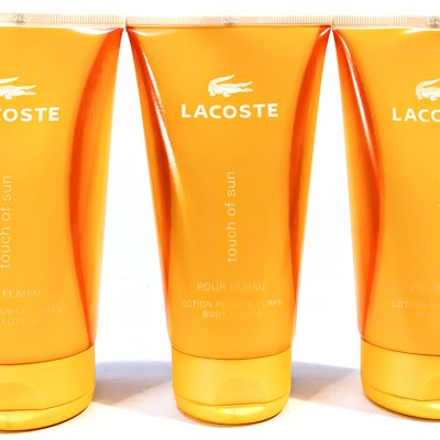 Three orange tubes of Lacoste Touch of Sun Pour Femme body lotion, each with a white Lacoste logo and text.