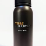 A bottle of Terre d'Hermès deodorant with a black cap and a brown cylindrical body with the brand name printed in orange and white.