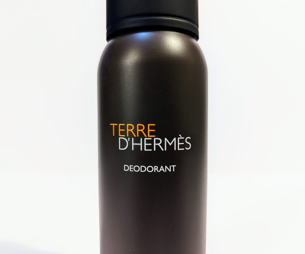 A bottle of Terre d'Hermès deodorant with a black cap and a brown cylindrical body with the brand name printed in orange and white.
