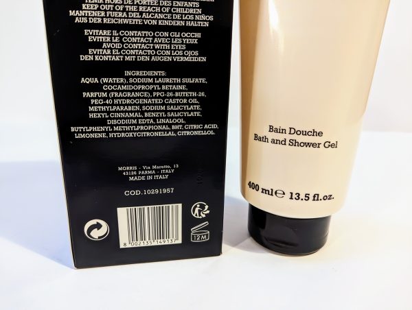 Close-up of a beige bottle labeled "Bain Douche Bath and Shower Gel" and a black box listing ingredients and product details. The bottle has a capacity of 400 ml (13.5 fl oz).