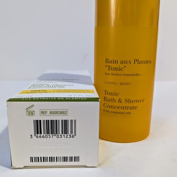 An image of a white box with product information next to a cylindrical yellow bottle labeled "Bain aux Plantes 'Tonic' - Tonic Bath & Shower Concentrate with essential oils.