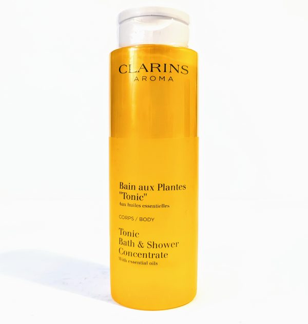 A bottle of Clarins Aroma Tonic Bath and Shower Concentrate with essential oils. The packaging is yellow and tall with white text.