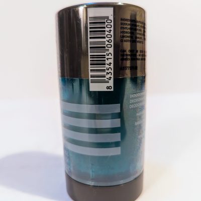 A cylindrical deodorant stick with a blue body and dark gray cap, displaying a barcode and ingredient list on the clear plastic wrapper. The label features three white horizontal lines.