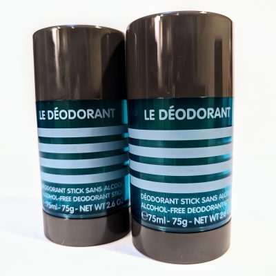 Two black deodorant sticks with teal labels displaying the product name "Le Déodorant" and information including "Alcohol-Free" and "Net Wt 2.6 oz / 75ml.