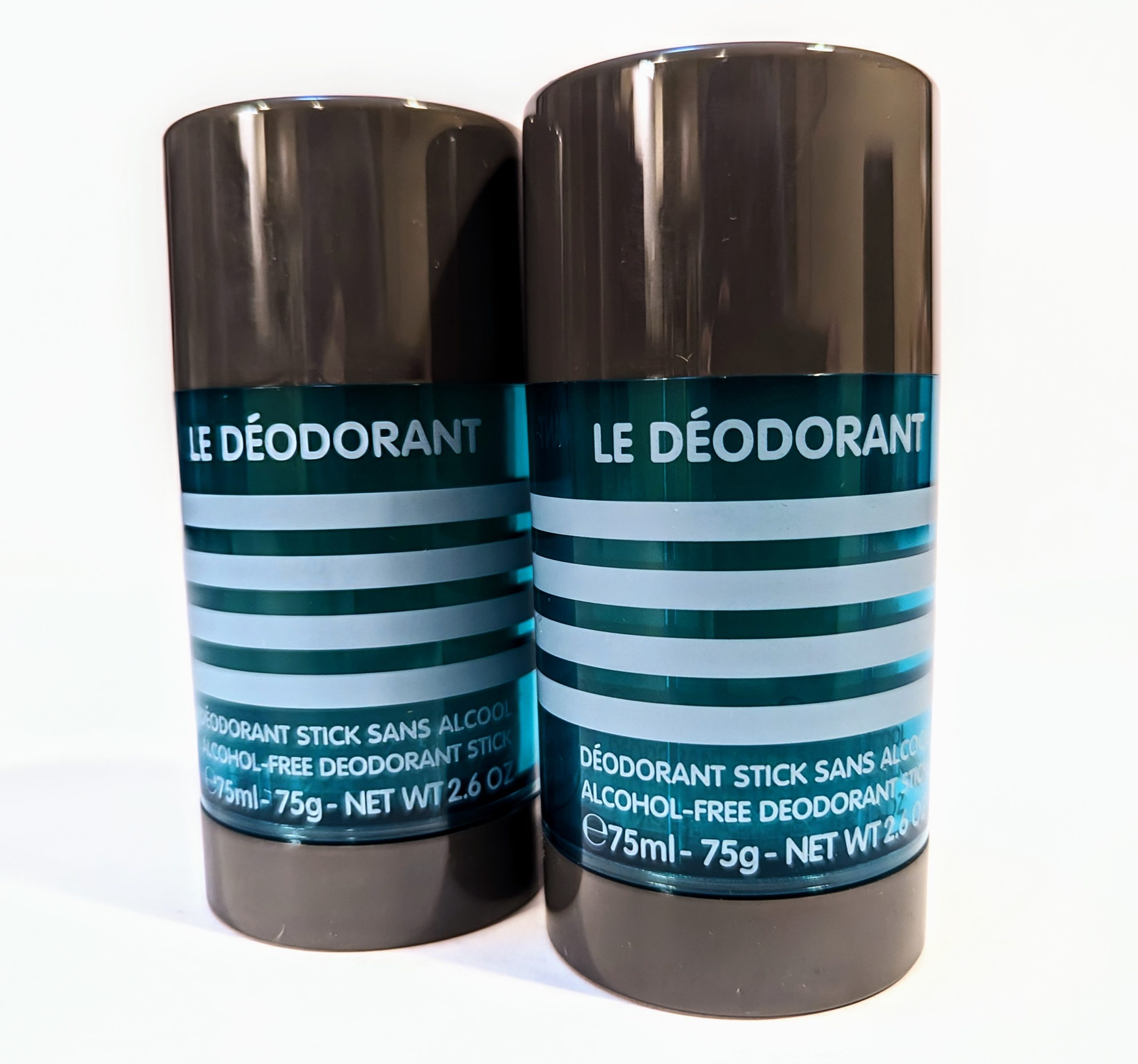 Two black deodorant sticks with teal labels displaying the product name “Le Déodorant” and information including “Alcohol-Free” and “Net Wt 2.6 oz / 75ml.