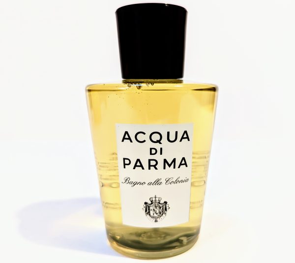 A bottle of Acqua di Parma Bagno alla Colonia is shown, featuring a yellowish liquid and a black cap. The label displays the brand's name and logo.