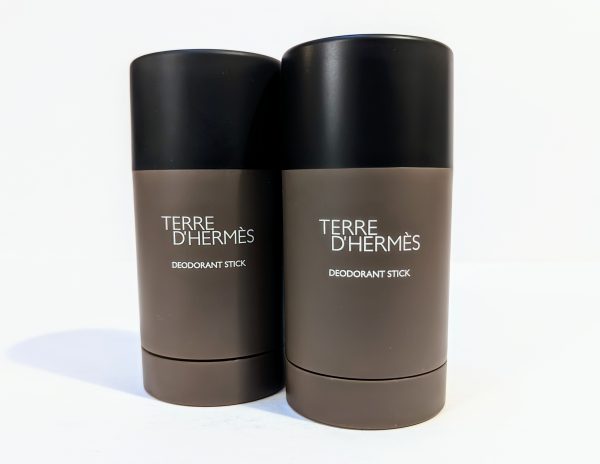 Two bottles of Terre d'Hermès deodorant sticks with brown containers and black caps stand side by side on a white background.