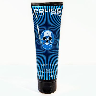 A tube of Police To Be All Over Body Shampoo, 100 ml, black with blue skull design and radiating blue lines.