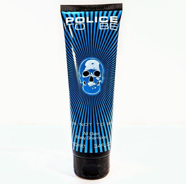 A tube of Police To Be All Over Body Shampoo, 100 ml, black with blue skull design and radiating blue lines.