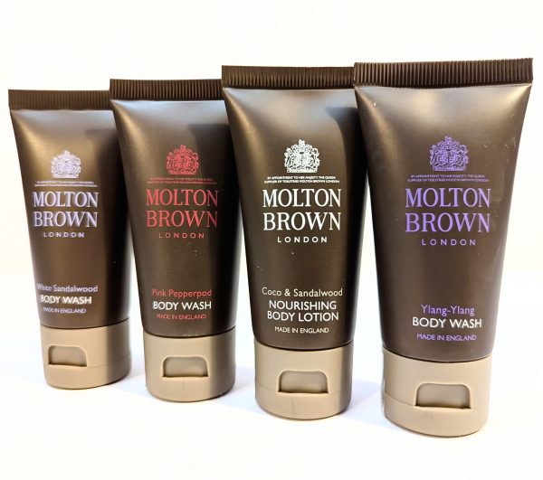 Four tubes of Molton Brown products arranged in a row, including White Sandalwood Body Wash, Pink Pepperpod Body Wash, Coco & Sandalwood Nourishing Body Lotion, and Ylang-Ylang Body Wash.