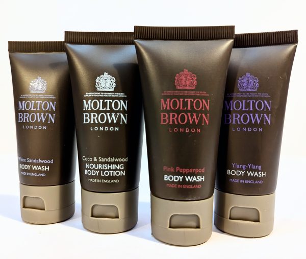 Four tubes of Molton Brown body care products are displayed. The products include White Sandalwood Body Wash, Coco & Sandalwood Nourishing Body Lotion, Pink Pepperpod Body Wash, and Ylang-Ylang Body Wash.