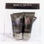 Clear plastic bag containing various Molton Brown body wash tubes labeled "Pink Pepperpod," "Ylang-Ylang," and "White Mulberry," with a black band on top displaying the brand name.