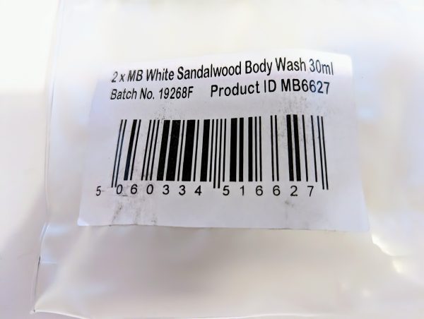 Close-up of a product label showing a barcode and details for "2 x MB White Sandalwood Body Wash 30ml," batch number 19268F, and product ID MB6627.