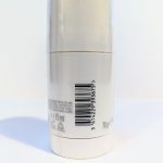 A white cylindrical container with a barcode and measurement details indicating 75ml. The bottom part has recycling symbols and the text "70g e" visible.