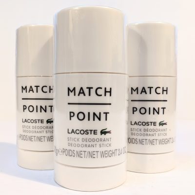 Three Lacoste Match Point stick deodorants are displayed upright, with the product name and logo visible on the front of each white container.