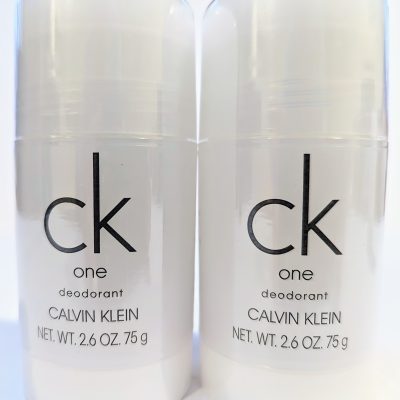Two sticks of Calvin Klein CK One deodorant, each weighing 2.6 ounces (75 grams), are placed side by side. The packaging is white with simple black text.