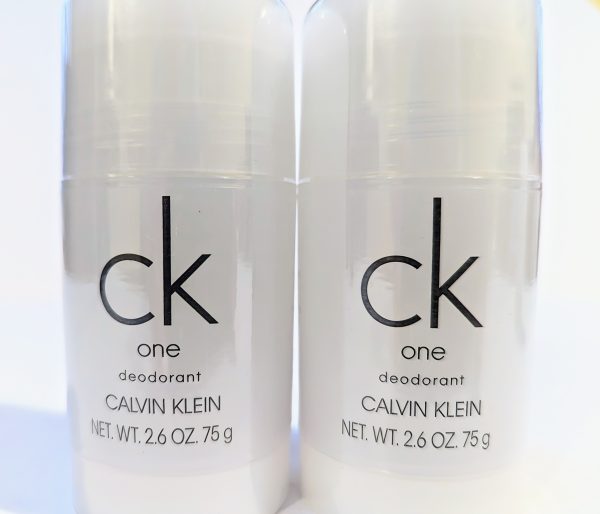 Two sticks of Calvin Klein CK One deodorant, each weighing 2.6 ounces (75 grams), are placed side by side. The packaging is white with simple black text.