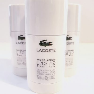 Three white Lacoste L.12.12 Blanc Pure deodorant stick containers are displayed, each holding 75 ml (2.4 oz). The containers have a green crocodile logo and product details written in black text.