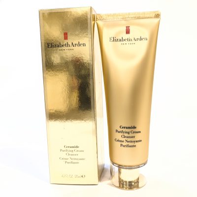 A tube of Elizabeth Arden Ceramide Purifying Cream Cleanser and its matching gold box, standing upright against a plain background. The tube is gold with black text.