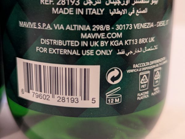 Close-up of a product label showing distribution, usage instructions, and recycling symbols. Includes a barcode and a 12-month expiration icon. Text indicates the product is made in Italy and distributed in the UK.