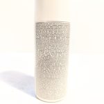 A close-up of a cylindrical container with a large block of small, densely packed text covering the entire visible side.